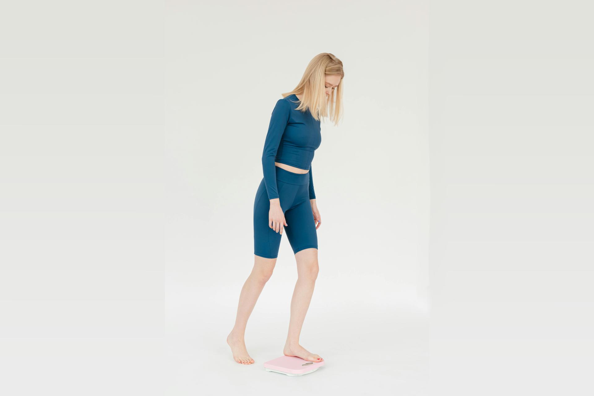 a woman in a blue top and shorts standing on a scale