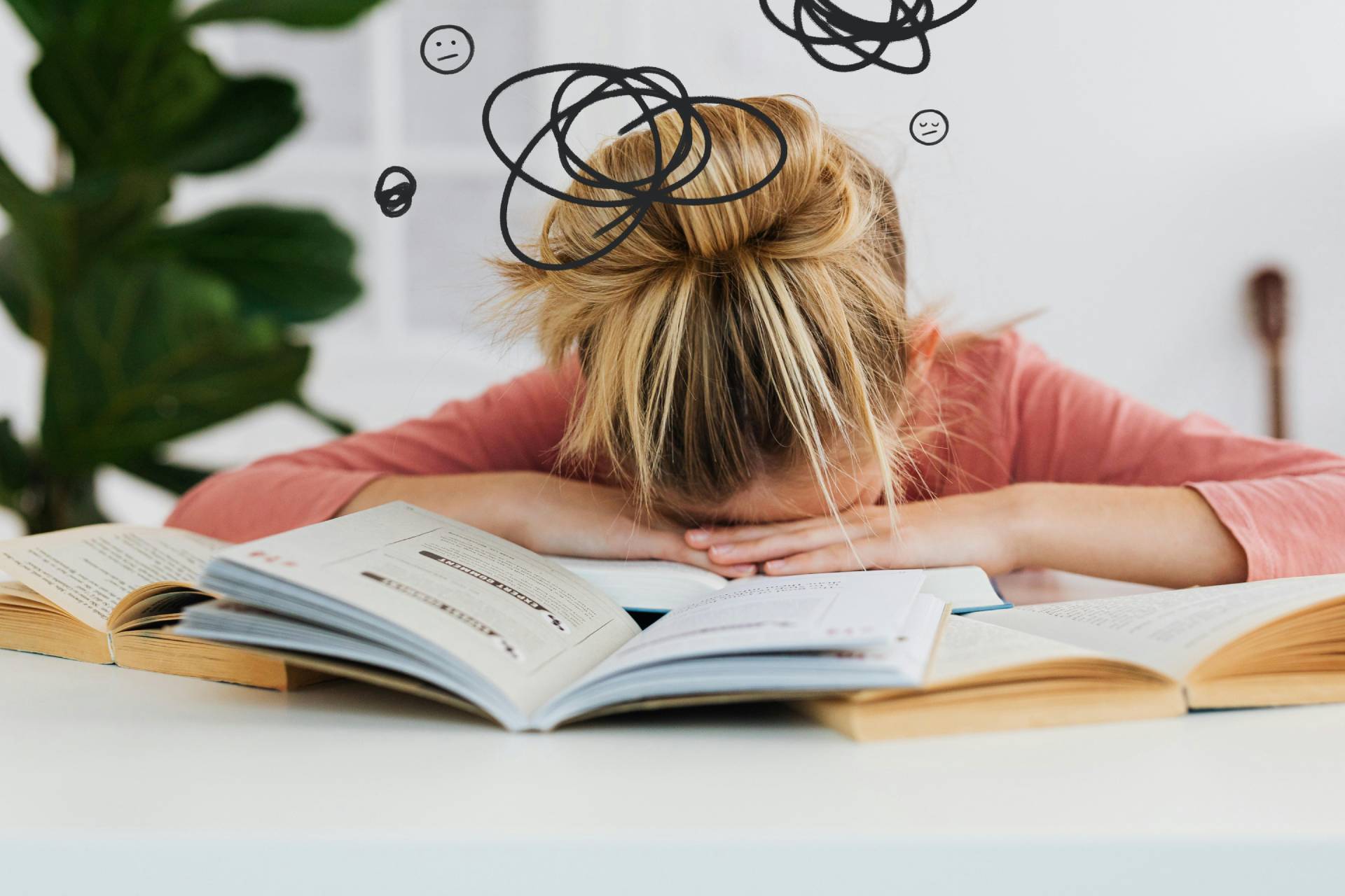a woman sitting at a table with her head on an open book