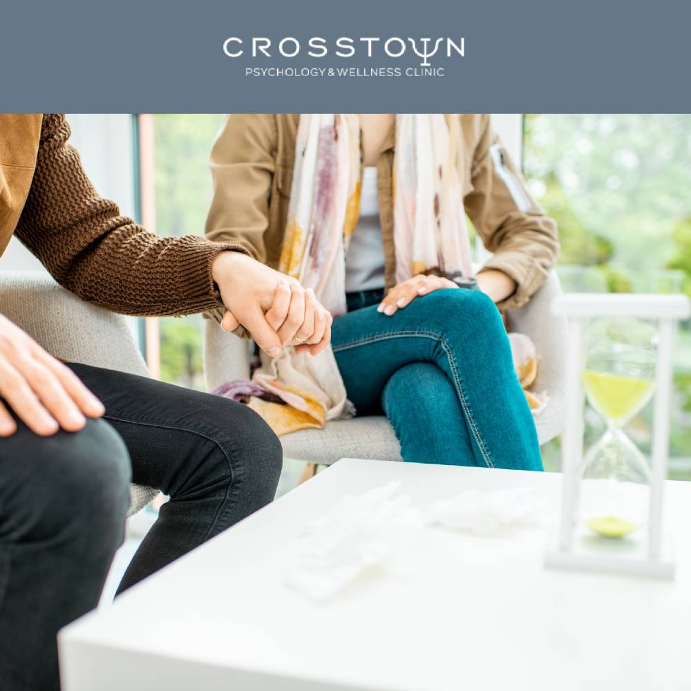 a couple of people sitting in chairs, holding hands