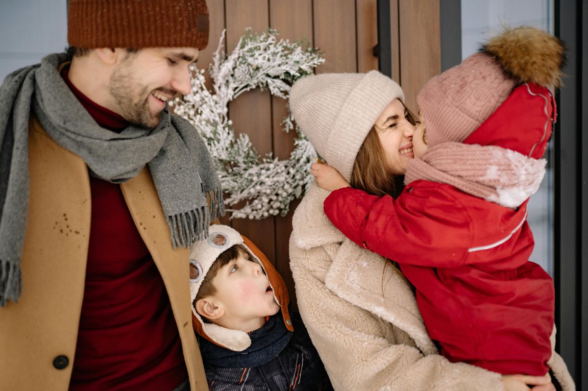 Family sharing a warm moment outdoors in winter clothing.