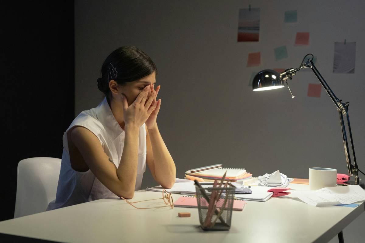 a woman sitting at a desk covering her face