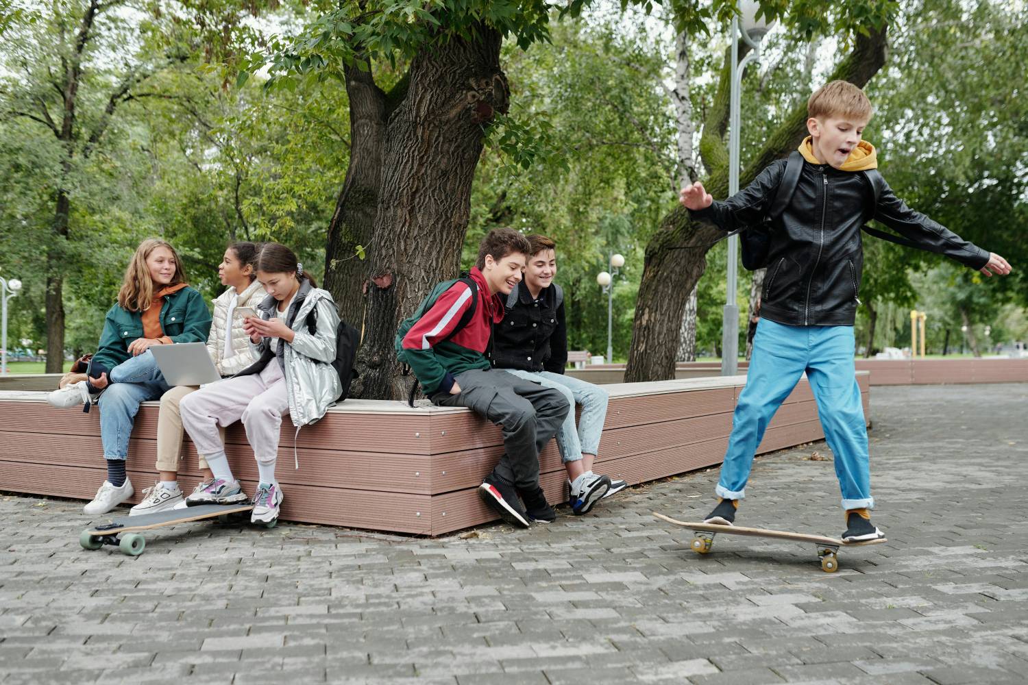 a group of kids sitting on a bench with a skateboard